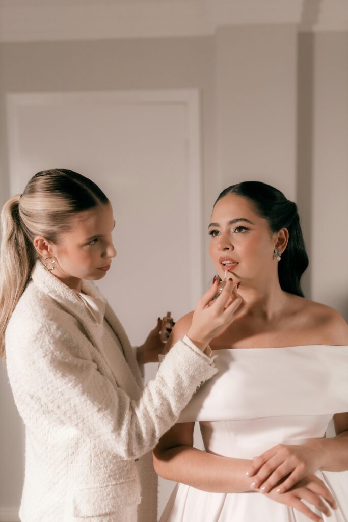 Bride receiving professional makeup application in a stylish indoor setting.