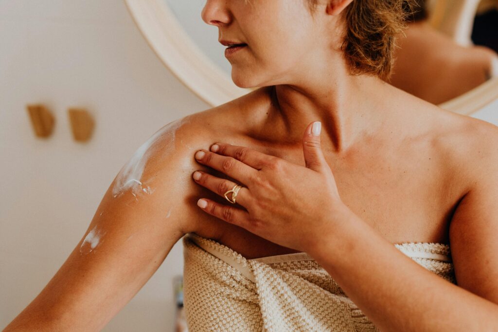 A woman applies body lotion for skincare, highlighting self-care and beauty routines.