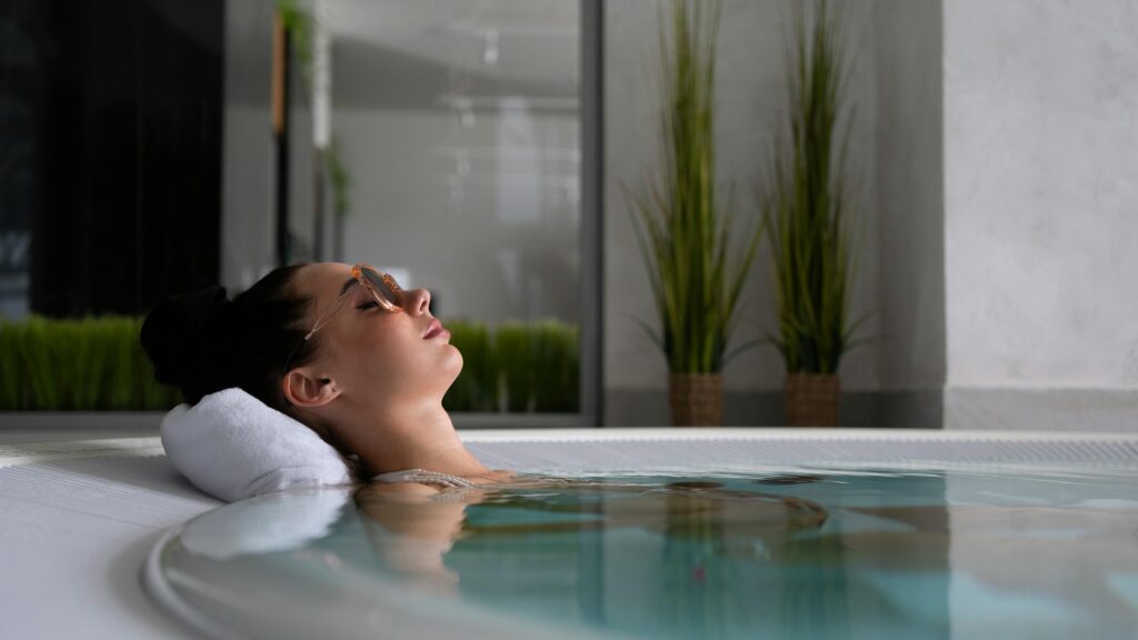 A woman relaxes in a jacuzzi with sunglasses, embodying self-care and relaxation.