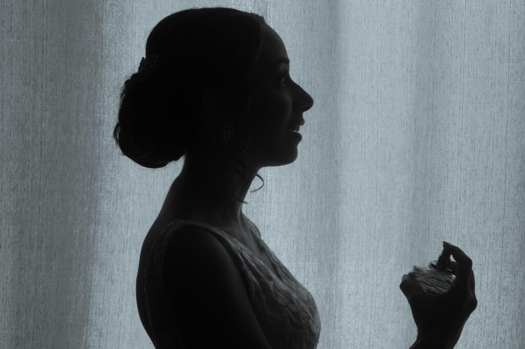 Silhouette of a bride holding perfume, exuding elegance and anticipation.